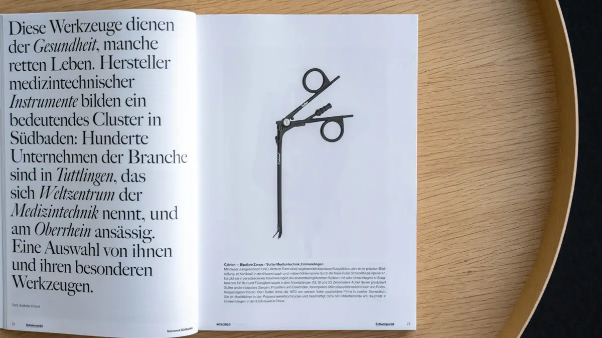 Offenes Magazin auf einem runden Holztisch, links Textseite und rechts eine schwarz-weiße Illustration einer Calvian® Bipolaren Zange