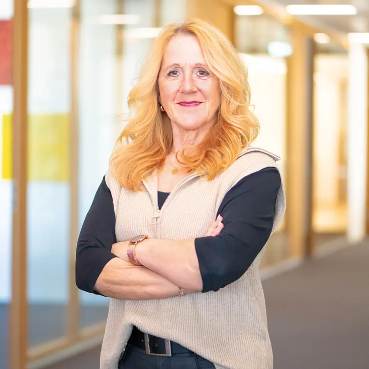 Blonde Frau mit verschränkten Armen steht im Flur von Sutter Medizintechnik – Mitarbeiterin im Empfangsbereich.