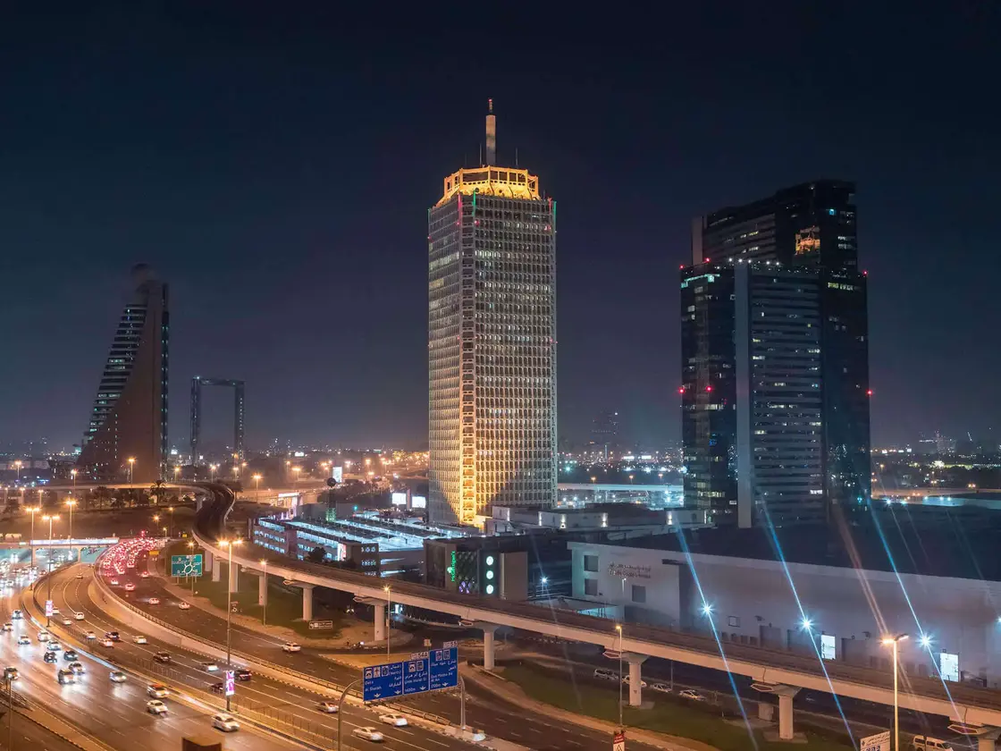 Dubai-Sheikh-Zayed-Road-Skyline-Nacht.jpg Nächtlicher Blick auf die Skyline von Dubai mit beleuchteten Hochhäusern und der Sheikh Zayed Road – modernes Stadtbild mit Verkehr und Architektur.
