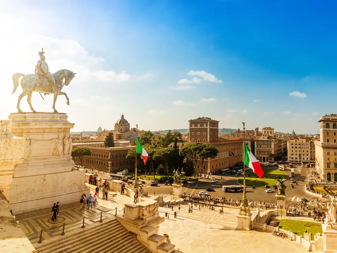 Panoramablick über Rom mit Reiterdenkmal am Vittorio‑Emanuele‑II.‑Monument, italienischen Flaggen und historischer Altstadt