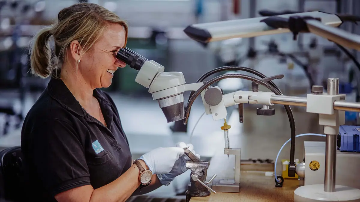 Eine Mitarbeiterin der Feinmechanik-Abteilung von Sutter Medizintechnik arbeitet konzentriert mit einem Mikroskop an einem medizinischen Instrument in der Produktion.