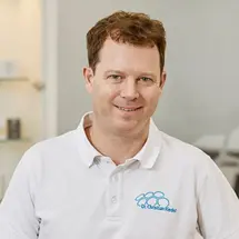 Person mit Brille und Hemd vor neutralem Hintergrund.