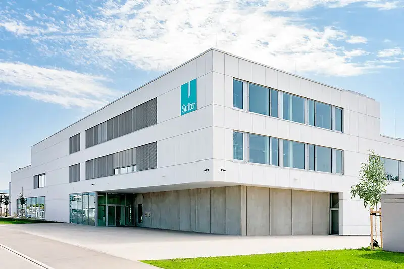 sutter-medizintechnik-unternehmenssitz-emmendingen.jpg Moderner Unternehmenssitz von Sutter Medizintechnik in Emmendingen mit weißer Fassade, großen Glasflächen und Sutter-Logo.