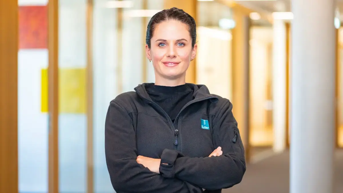 Franziska Beck mit verschränkten Armen im Flur von Sutter Medizintechnik – Ausbilderin in der Feinmechanik.